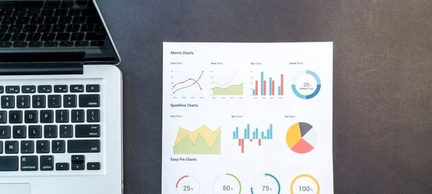 Printed charts and graphs beside a laptop, SEO analytics and reporting